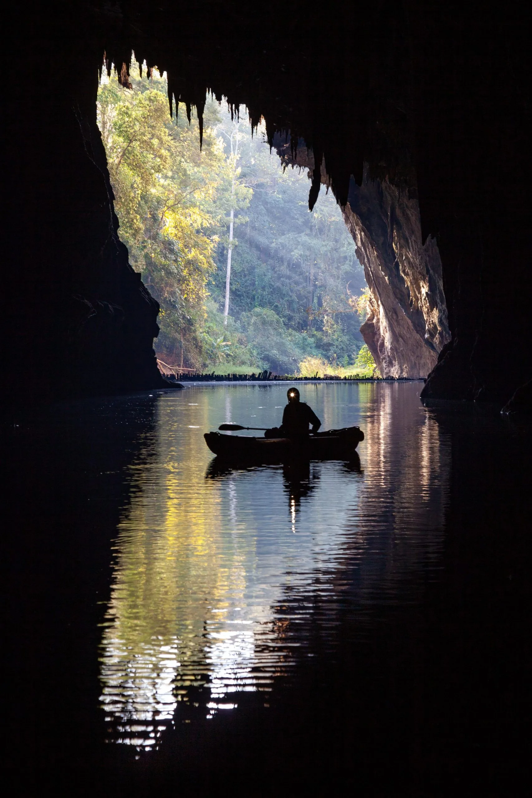 Boat silhouetted on still water at a cave exit