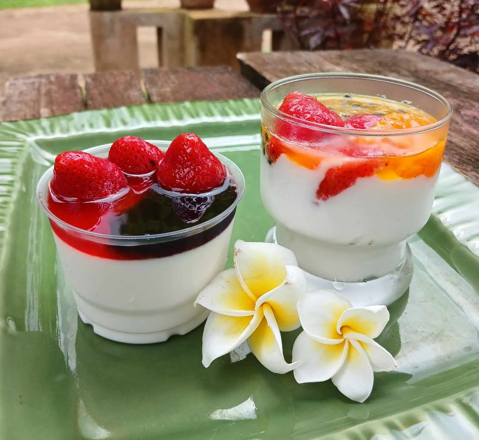 Two glasses of home-made yogurt with strawberries and frangipani flowers