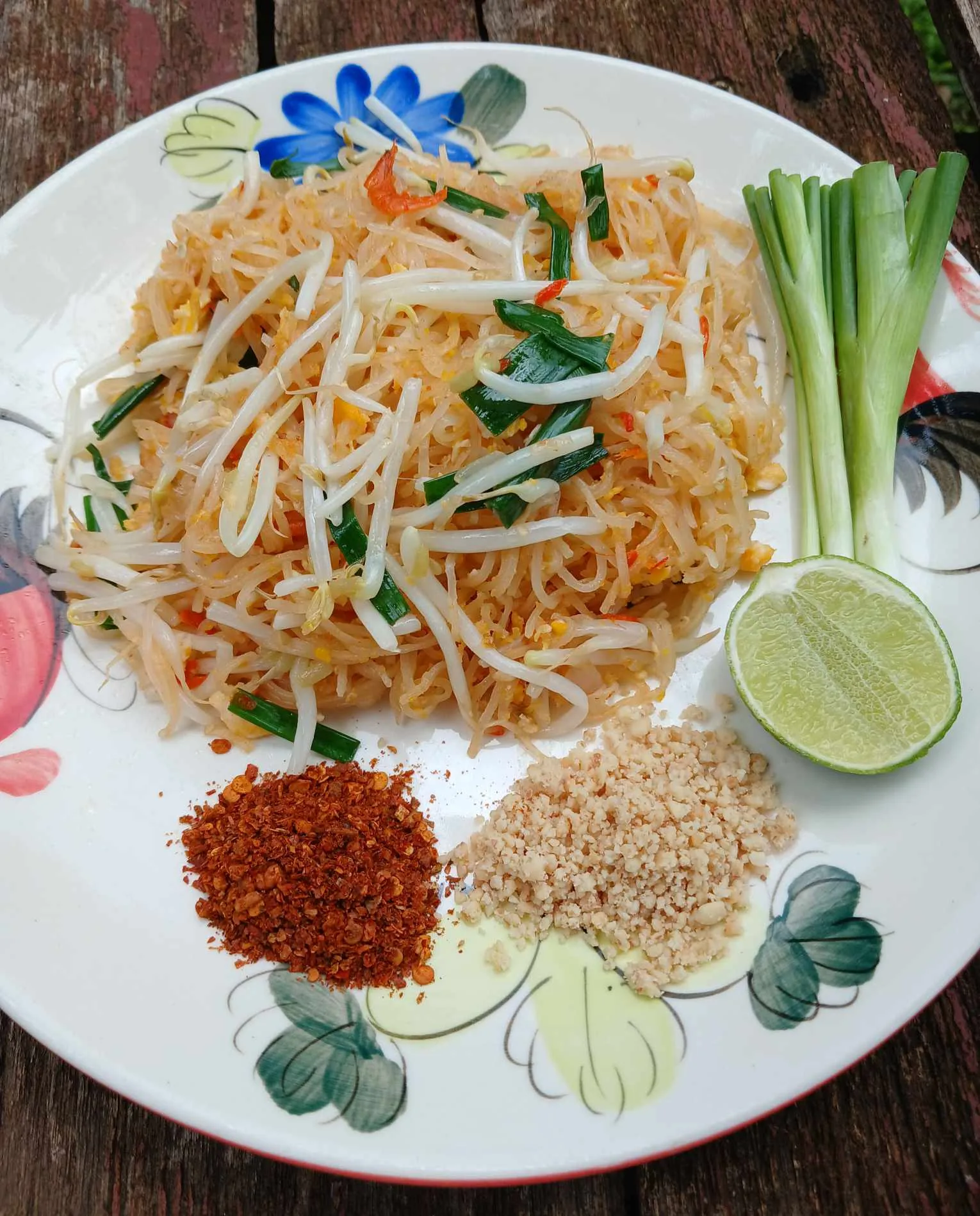 Plate of pad Thai with lime, crushed peanuts and chilli